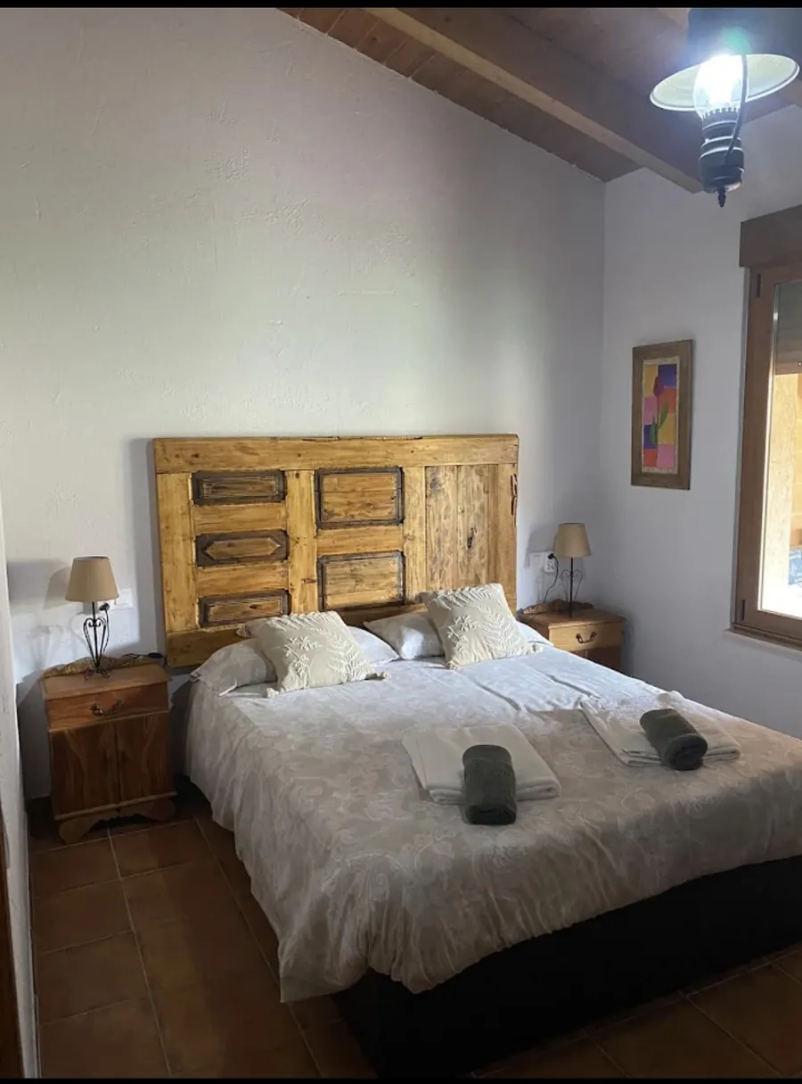 Habitación de matrimonio con cabecero de madera maciza