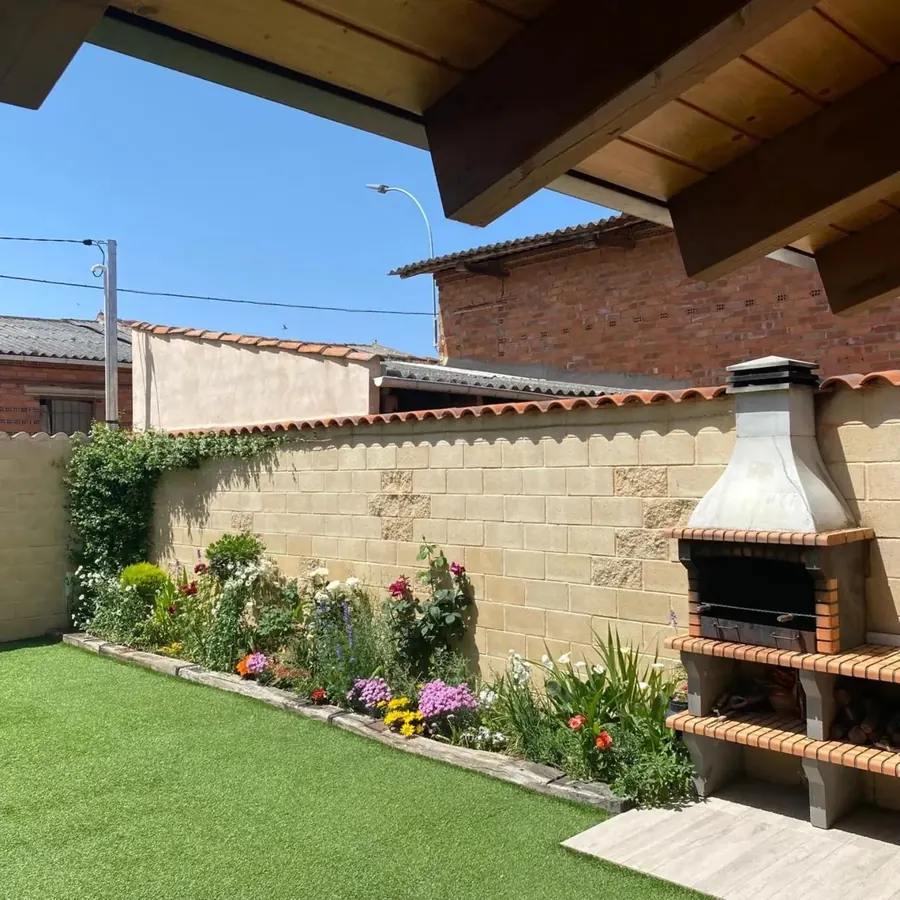 Jardín florido junto a la barbacoa de piedra